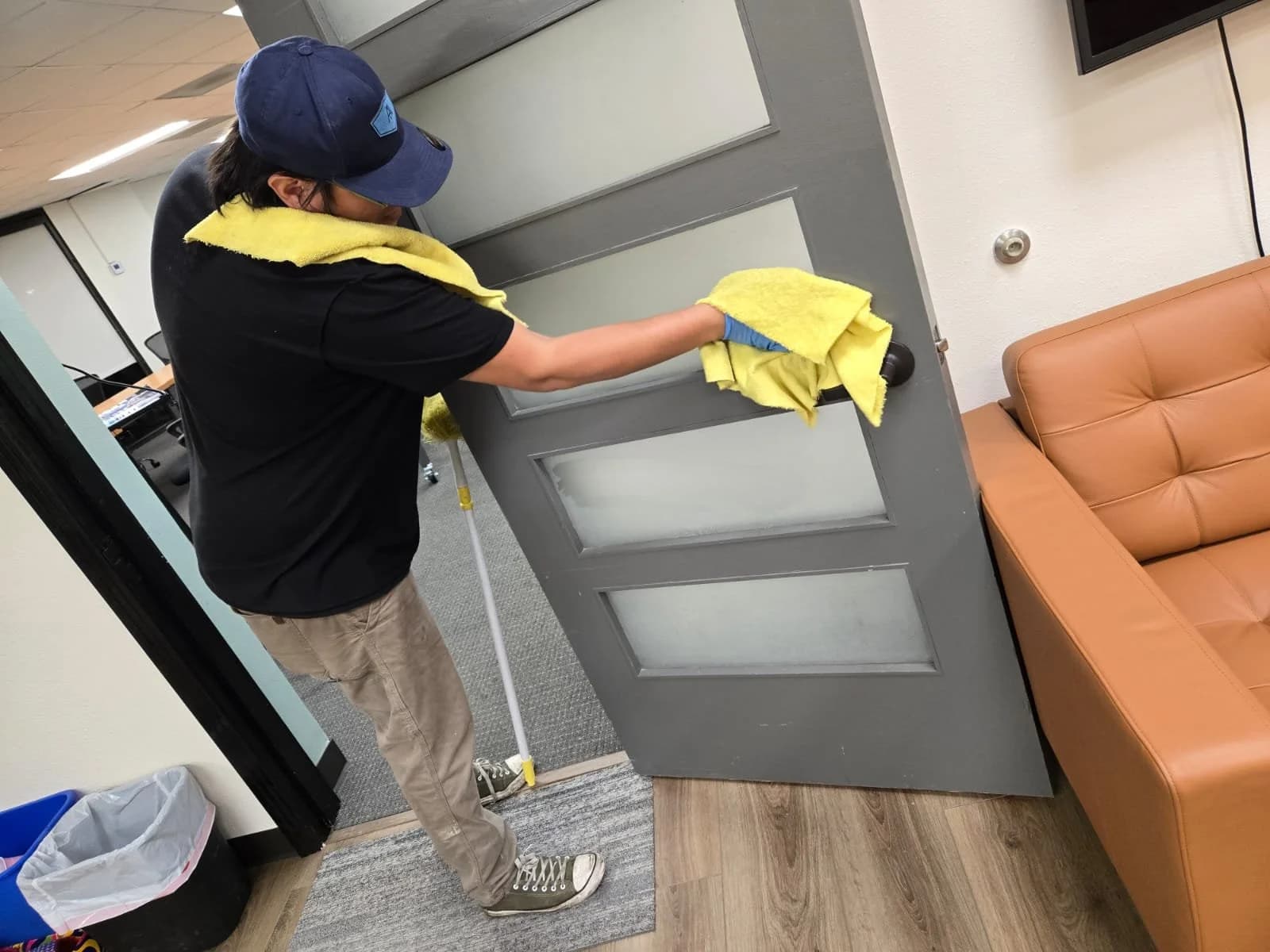 Technician cleaning commercial restroom surfaces with microfiber cloth